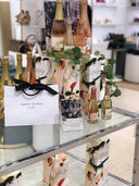 Bottles of Nude and Blush Sparkling wine in Harvey Nichols shop setting with shopping bag